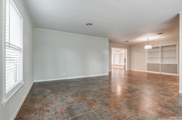 unfurnished room featuring ornamental molding and built in shelves