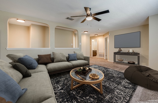 carpeted living room with ceiling fan, visible vents, and a textured ceiling