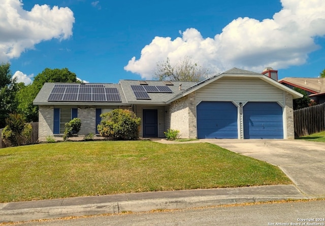 view of front facade with a front yard, solar panels, and a garage