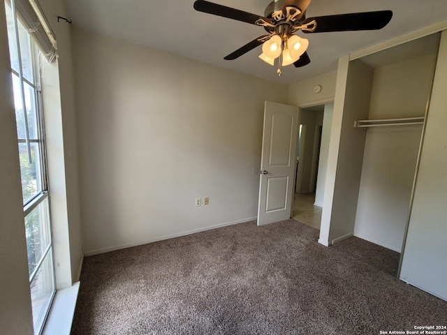 unfurnished bedroom with multiple windows, dark colored carpet, and ceiling fan