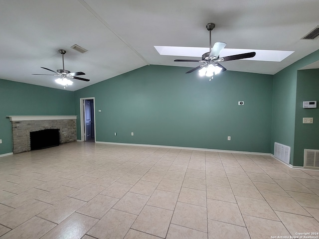 unfurnished living room featuring ceiling fan, light tile patterned flooring, and vaulted ceiling with skylight