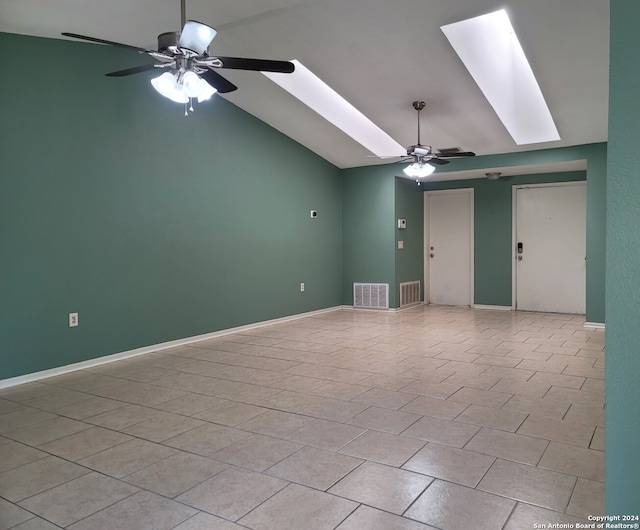 unfurnished room featuring vaulted ceiling with skylight, ceiling fan, and light tile patterned floors