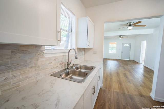 kitchen with tasteful backsplash, white cabinets, ceiling fan, hardwood / wood-style flooring, and sink