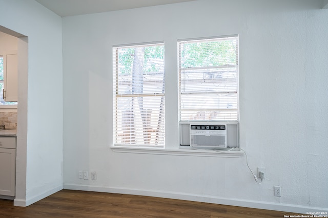 empty room featuring cooling unit, dark wood-type flooring, and plenty of natural light