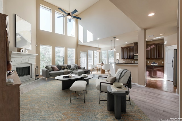 living room featuring ceiling fan, high vaulted ceiling, and light wood-type flooring