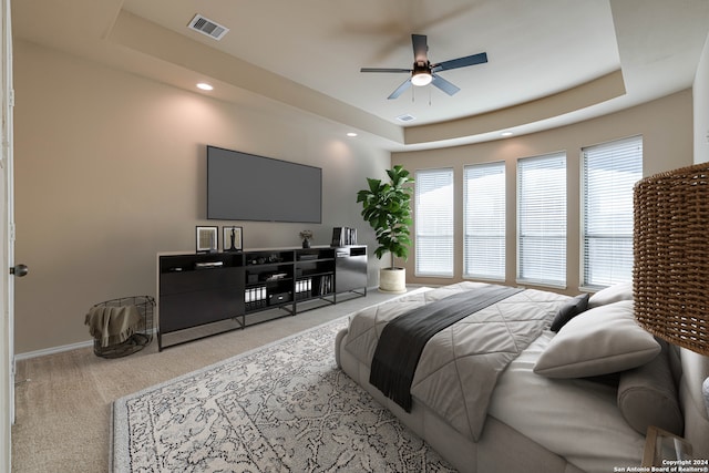 bedroom featuring ceiling fan, a raised ceiling, and light colored carpet