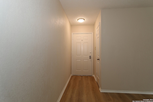 hallway featuring wood-type flooring and a textured ceiling