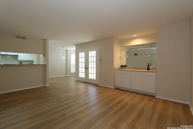 unfurnished living room featuring a textured ceiling, hardwood / wood-style floors, and french doors