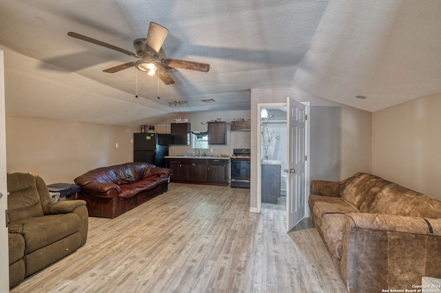 living room featuring light wood-type flooring, a textured ceiling, lofted ceiling, and ceiling fan