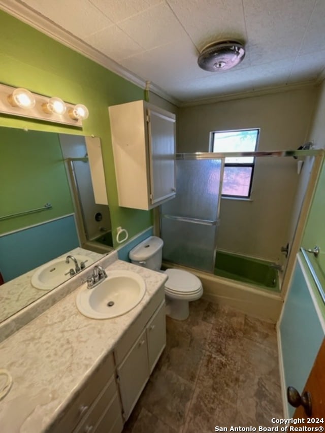 full bathroom with ornamental molding, vanity, toilet, and bath / shower combo with glass door