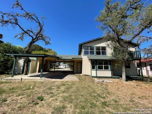 rear view of house featuring a yard and a carport