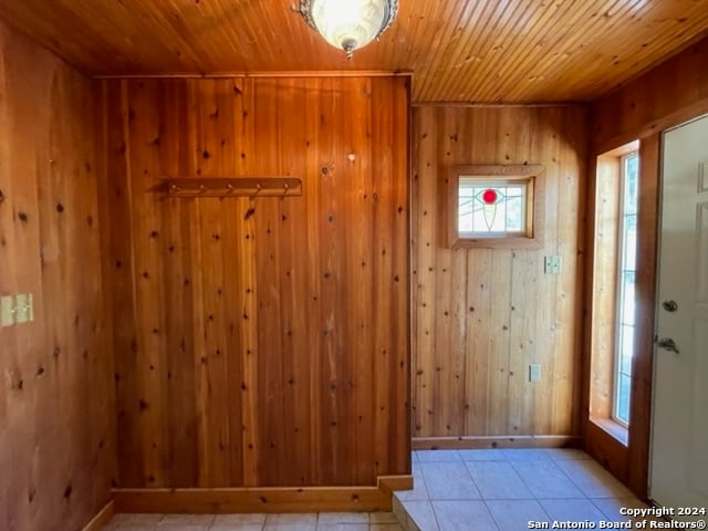 interior space featuring wood ceiling, wood walls, and light tile patterned floors