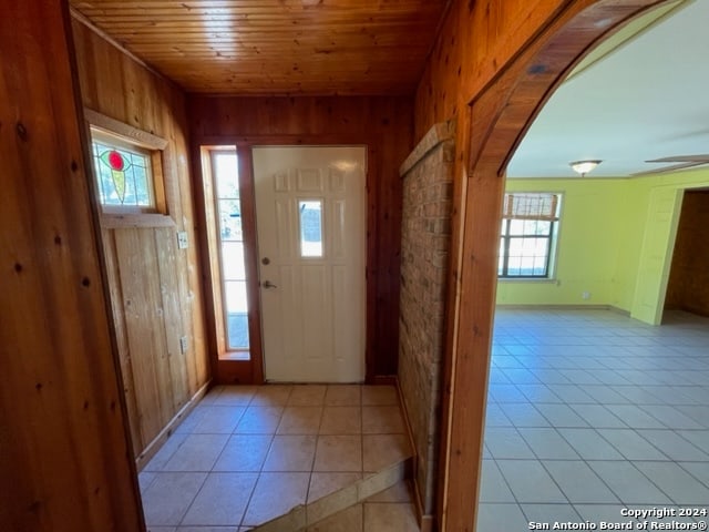 foyer featuring wood walls, light tile patterned floors, and a wealth of natural light