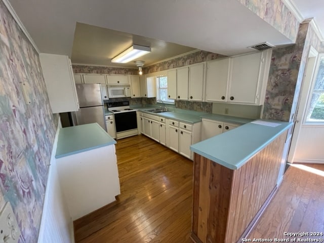 kitchen featuring white cabinets, white appliances, hardwood / wood-style flooring, and sink