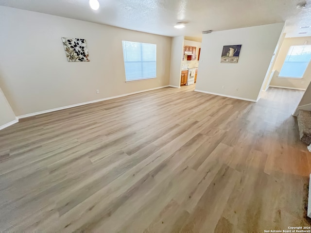 unfurnished living room featuring a textured ceiling and light hardwood / wood-style flooring