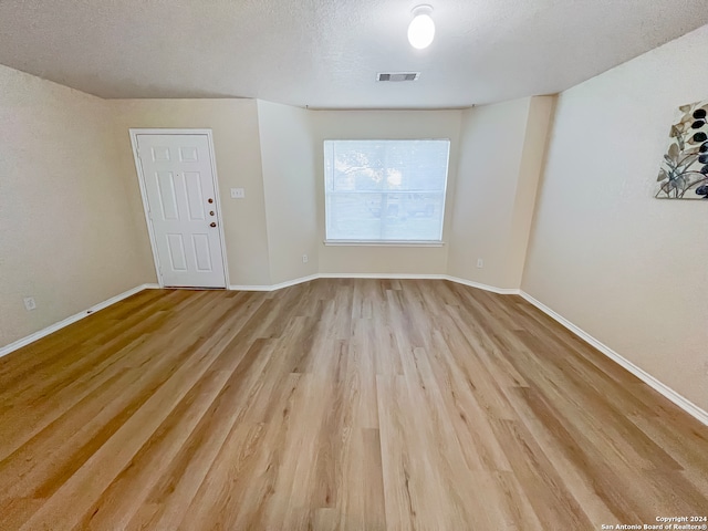 empty room featuring light wood-type flooring and a textured ceiling