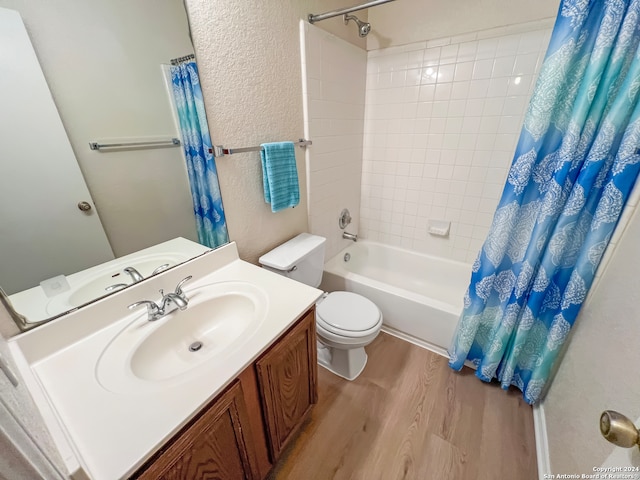 full bathroom with shower / tub combo with curtain, hardwood / wood-style flooring, vanity, and toilet