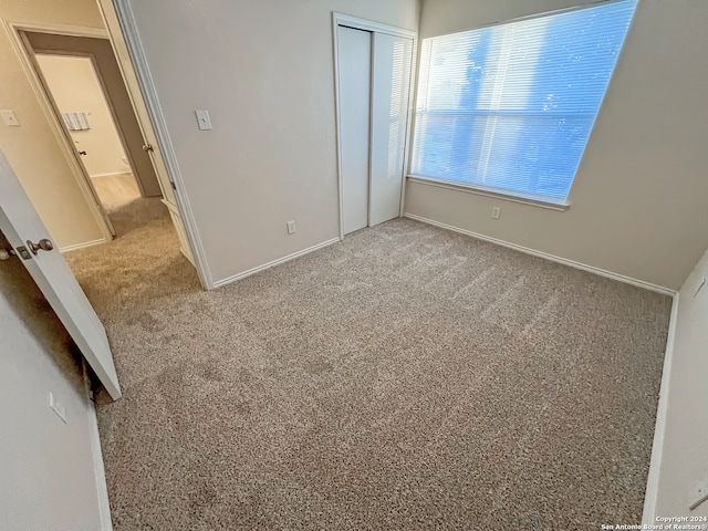 unfurnished bedroom with light carpet and a closet