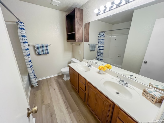 full bathroom featuring vanity, shower / bath combination with curtain, a textured ceiling, toilet, and hardwood / wood-style floors