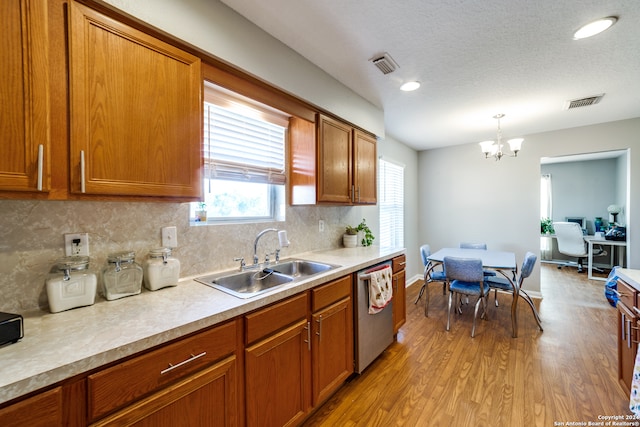 kitchen featuring pendant lighting, light hardwood / wood-style floors, sink, decorative backsplash, and stainless steel dishwasher