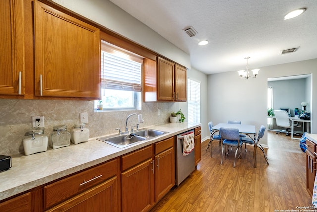 kitchen featuring visible vents, dishwasher, light countertops, a sink, and brown cabinets