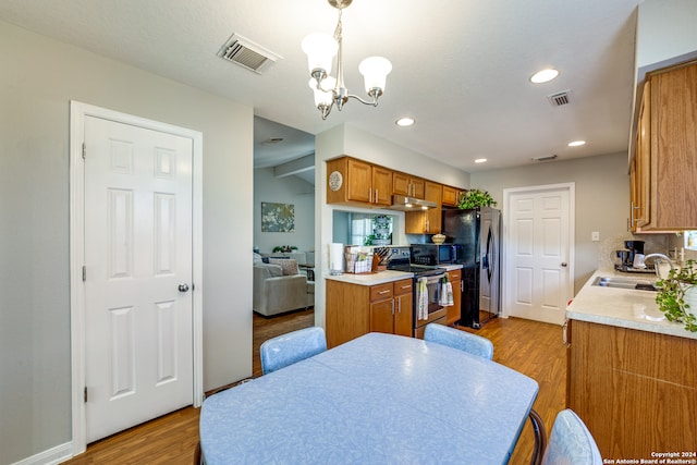 kitchen featuring stainless steel appliances, light wood-type flooring, an inviting chandelier, decorative light fixtures, and sink