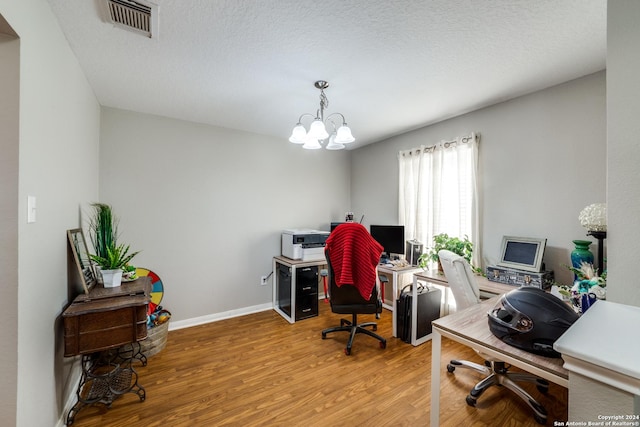 home office with an inviting chandelier, a textured ceiling, visible vents, wood finished floors, and baseboards