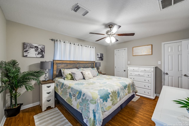 bedroom with ceiling fan, a textured ceiling, and dark hardwood / wood-style floors