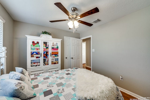 bedroom with ceiling fan, hardwood / wood-style flooring, and a textured ceiling