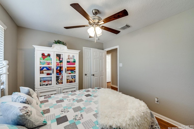 bedroom featuring ceiling fan, visible vents, baseboards, and wood finished floors