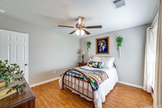 bedroom with light wood-style floors, baseboards, visible vents, and a ceiling fan