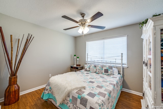 bedroom featuring ceiling fan, dark hardwood / wood-style floors, and a textured ceiling