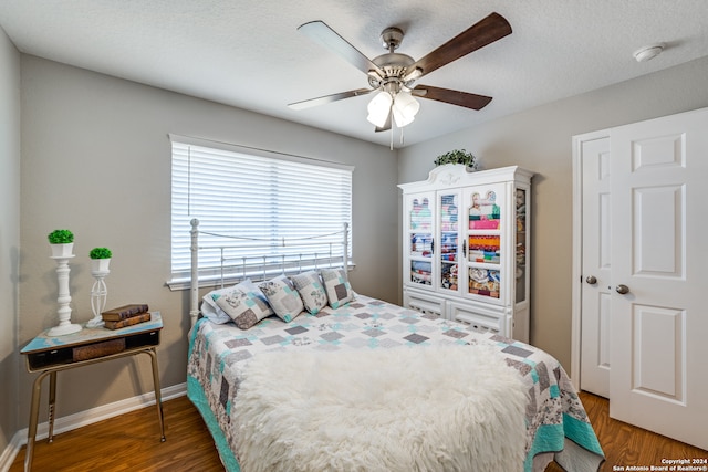 bedroom with ceiling fan, a textured ceiling, and dark hardwood / wood-style flooring