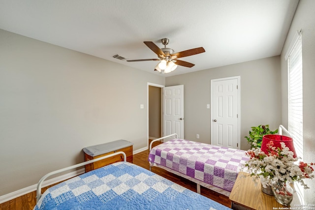 bedroom featuring visible vents, baseboards, a ceiling fan, and wood finished floors