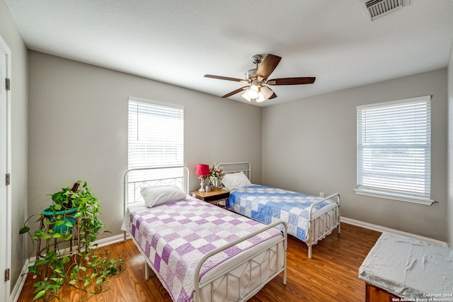 bedroom with hardwood / wood-style floors, multiple windows, and ceiling fan