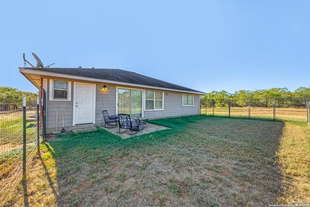 back of house with a fenced backyard and a lawn