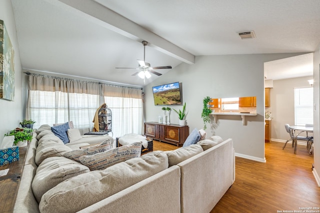 living room featuring visible vents, baseboards, lofted ceiling with beams, ceiling fan, and wood finished floors