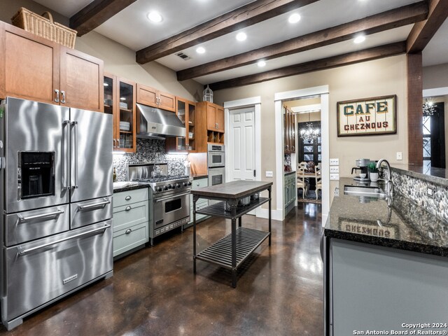 kitchen with beamed ceiling, high quality appliances, dark stone countertops, sink, and backsplash