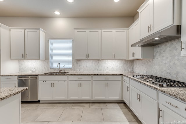 kitchen with tasteful backsplash, sink, white cabinetry, stainless steel appliances, and light stone countertops