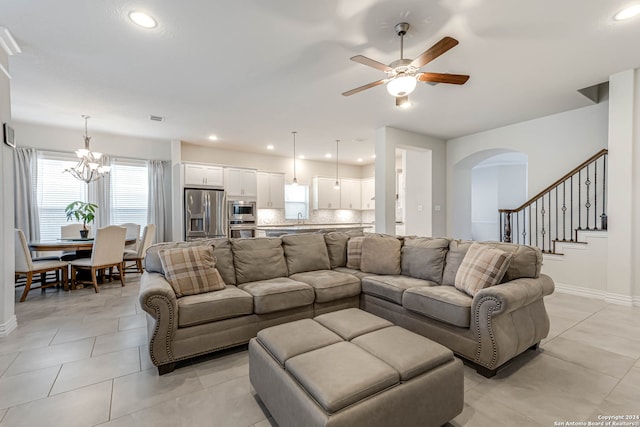 tiled living room with ceiling fan with notable chandelier and sink