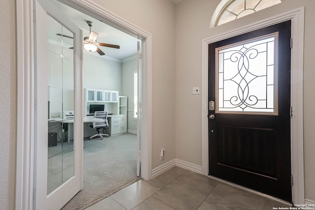 foyer with crown molding, carpet, and ceiling fan