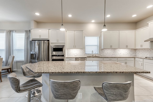 kitchen with stainless steel appliances, white cabinetry, and decorative light fixtures