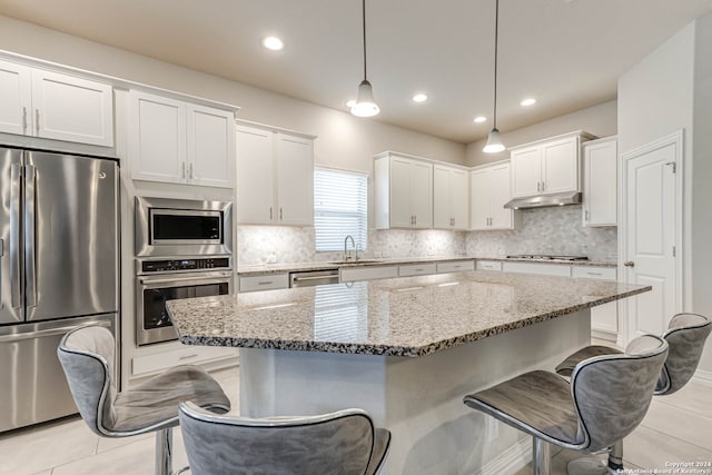 kitchen featuring a kitchen island, white cabinetry, stainless steel appliances, and decorative light fixtures