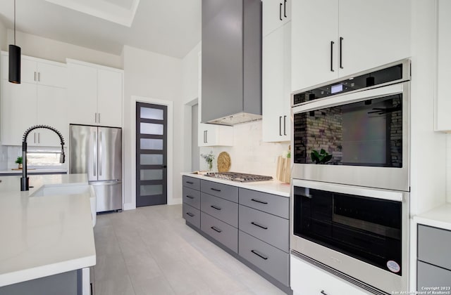 kitchen with pendant lighting, backsplash, white cabinetry, gray cabinets, and appliances with stainless steel finishes