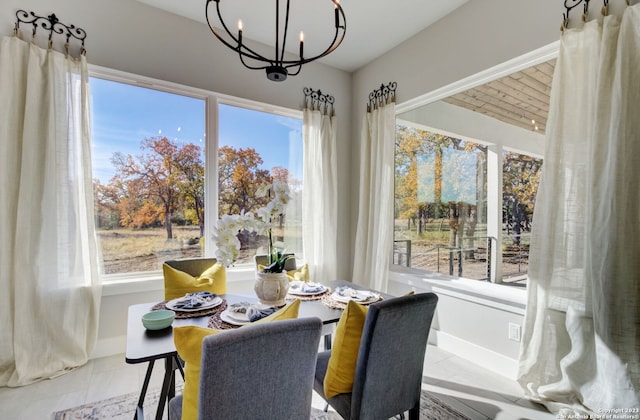 tiled dining room featuring a chandelier and a healthy amount of sunlight