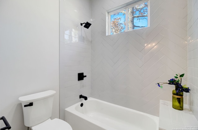 bathroom featuring tiled shower / bath combo and toilet