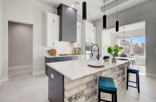 kitchen with appliances with stainless steel finishes, a breakfast bar area, gray cabinets, decorative light fixtures, and sink