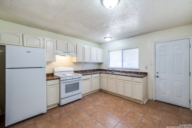 kitchen featuring a textured ceiling, white appliances, sink, and light tile patterned floors