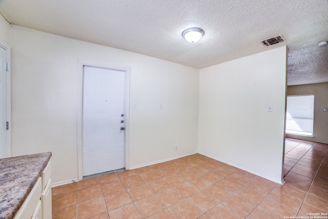 tiled empty room featuring a textured ceiling