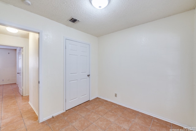 unfurnished bedroom featuring a textured ceiling, a closet, and light tile patterned floors